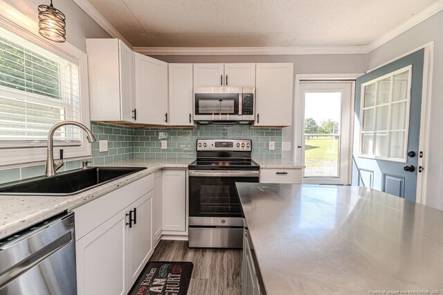 4101 Carson Dr, Sanford, NC 27332 - kitchen featuring appliances with stainless steel finishes, crown molding, white cabinets, backsplash, and healthy amount of natural light
