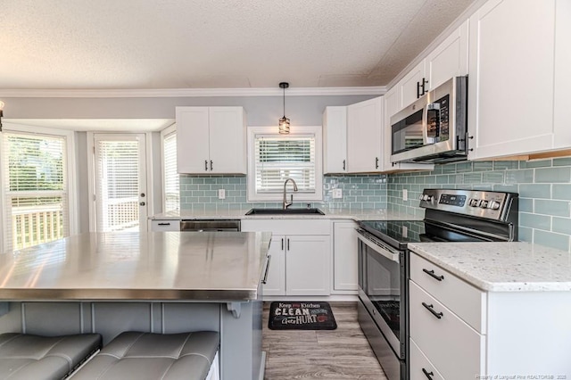 4101 Carson Dr, Sanford, NC 27332 - kitchen featuring stainless steel appliances, a textured ceiling, crown molding, a kitchen bar, and white cabinetry