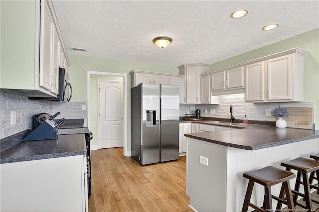 167 Westminster Dr, Raeford, NC 28376 - kitchen featuring stainless steel refrigerator with ice dispenser, a peninsula, dark countertops, a breakfast bar area, and decorative backsplash