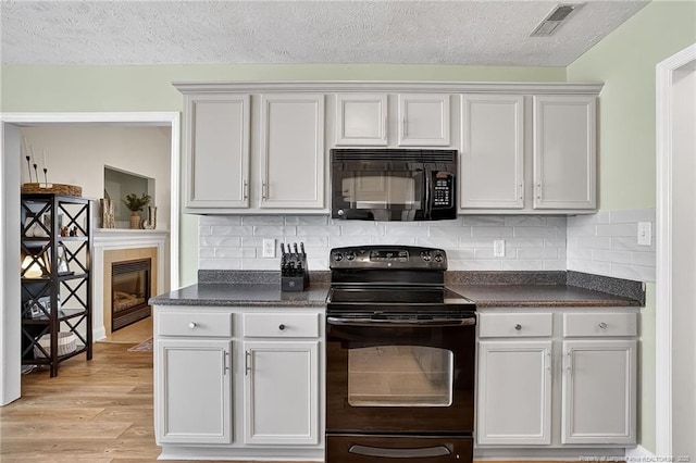 167 Westminster Dr, Raeford, NC 28376 - kitchen with black appliances, dark countertops, light wood-style floors, backsplash, and a textured ceiling