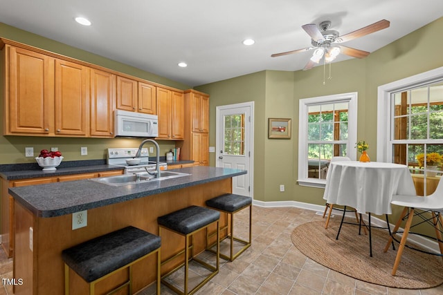 126 Captains Ct, Durham, NC 27712 - kitchen with white appliances, dark countertops, a kitchen bar, recessed lighting, and an island with sink