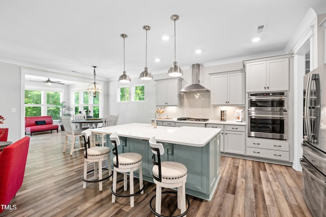 8341 Running Fern Way, Willow Springs, NC 27592 - kitchen with wall chimney exhaust hood, stainless steel appliances, light countertops, backsplash, and light wood-style floors
