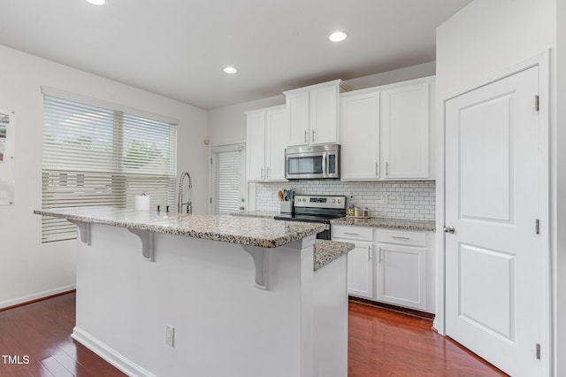 543 Callandale Ln, Durham, NC 27703 - kitchen featuring appliances with stainless steel finishes, a breakfast bar, dark wood-style flooring, backsplash, and an island with sink