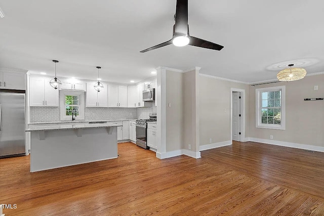 2609 Elmhurst Cir, Raleigh, NC 27610 - kitchen featuring stainless steel appliances, decorative backsplash, crown molding, white cabinets, and a kitchen island