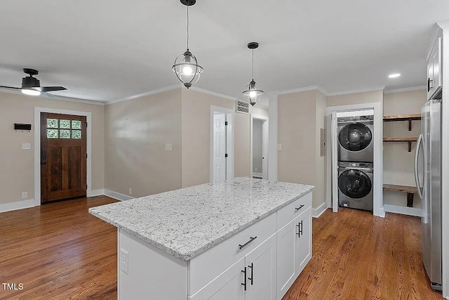 2609 Elmhurst Cir, Raleigh, NC 27610 - kitchen featuring stacked washing machine and dryer, freestanding refrigerator, a kitchen island, ceiling fan, and wood finished floors