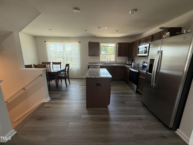 4500 Black Drum Dr, Raleigh, NC 27616 - kitchen featuring appliances with stainless steel finishes, a kitchen island, dark brown cabinetry, dark wood-style flooring, and light stone countertops