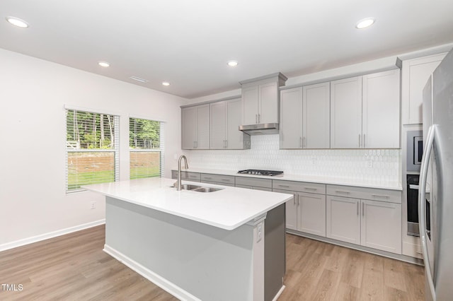 1113 Umstead Grove Way, Durham, NC 27712 - kitchen featuring gray cabinetry, stainless steel appliances, under cabinet range hood, backsplash, and light wood-style floors