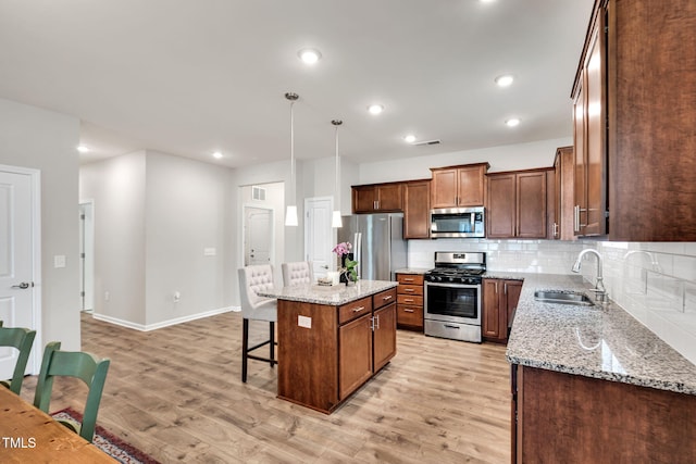 4102 Catfish Way, Durham, NC 27703 - kitchen featuring appliances with stainless steel finishes, a kitchen bar, light wood-style floors, a center island, and tasteful backsplash