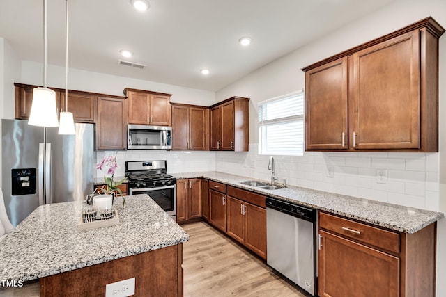 4102 Catfish Way, Durham, NC 27703 - kitchen featuring appliances with stainless steel finishes, light stone counters, light wood-style floors, a kitchen island, and hanging light fixtures