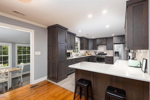 256 Marilyn Cir, Cary, NC 27513 - kitchen with stainless steel appliances, a peninsula, light countertops, light wood-style floors, and crown molding