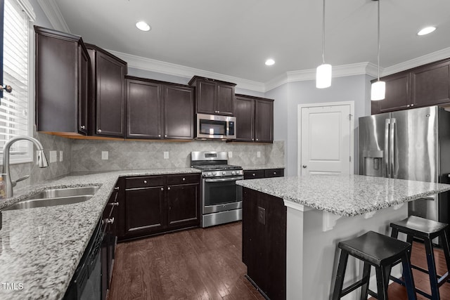 184 Elgin Ct, Burlington, NC 27215 - kitchen featuring appliances with stainless steel finishes, a center island, a breakfast bar, dark brown cabinets, and light stone countertops
