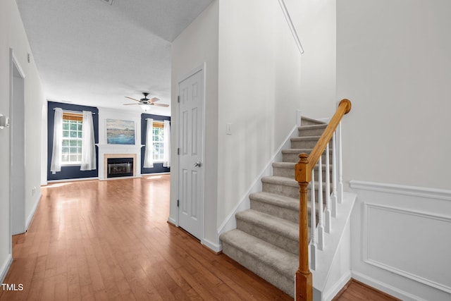 110 Bonhill Ct, Apex, NC 27502 - stairway featuring hardwood / wood-style flooring, ceiling fan, and a fireplace