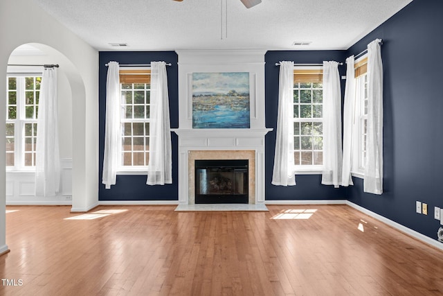 110 Bonhill Ct, Apex, NC 27502 - unfurnished living room with a ceiling fan, a textured ceiling, hardwood / wood-style floors, plenty of natural light, and a fireplace with flush hearth