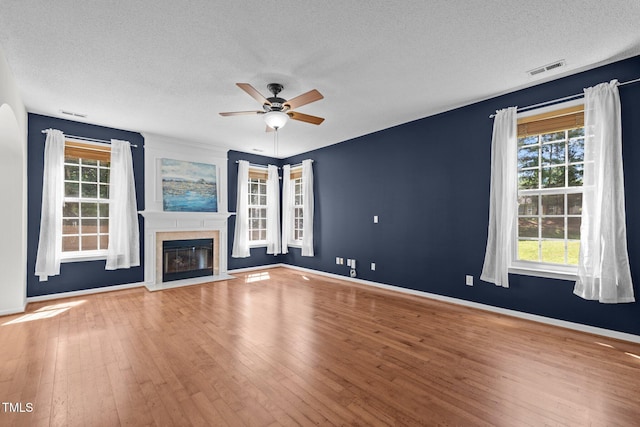 110 Bonhill Ct, Apex, NC 27502 - unfurnished living room featuring a ceiling fan, a textured ceiling, wood finished floors, and a fireplace with flush hearth