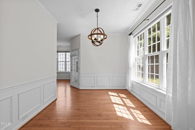 110 Bonhill Ct, Apex, NC 27502 - unfurnished dining area featuring ornamental molding, a chandelier, a decorative wall, a wainscoted wall, and light wood-style floors