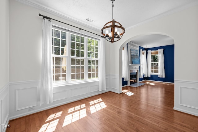 110 Bonhill Ct, Apex, NC 27502 - unfurnished dining area featuring a chandelier, wainscoting, crown molding, hardwood / wood-style flooring, and arched walkways