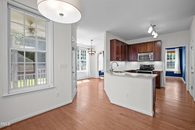 110 Bonhill Ct, Apex, NC 27502 - kitchen featuring appliances with stainless steel finishes, decorative backsplash, light wood-type flooring, light countertops, and plenty of natural light