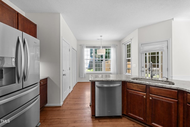 110 Bonhill Ct, Apex, NC 27502 - kitchen featuring appliances with stainless steel finishes, hardwood / wood-style flooring, light stone countertops, and pendant lighting