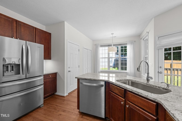 110 Bonhill Ct, Apex, NC 27502 - kitchen with stainless steel appliances, wood finished floors, light stone countertops, and hanging light fixtures
