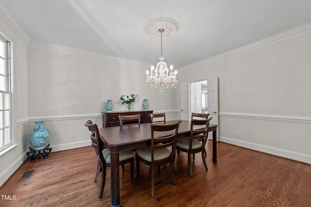 1105 Tazwell Pl, Raleigh, NC 27612 - dining room with a chandelier, plenty of natural light, ornamental molding, and wood finished floors