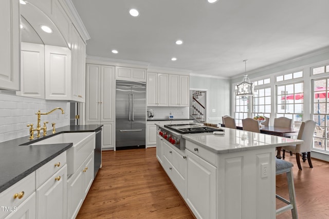 1105 Tazwell Pl, Raleigh, NC 27612 - kitchen featuring appliances with stainless steel finishes, tasteful backsplash, a chandelier, white cabinetry, and crown molding