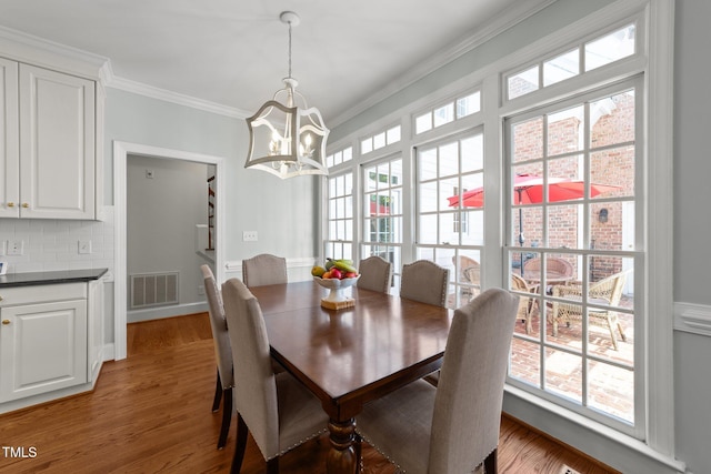 1105 Tazwell Pl, Raleigh, NC 27612 - dining area featuring a chandelier, crown molding, and light wood-style floors