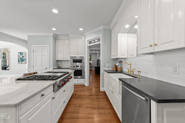 1105 Tazwell Pl, Raleigh, NC 27612 - kitchen with appliances with stainless steel finishes, ornamental molding, white cabinetry, dark wood-style floors, and backsplash