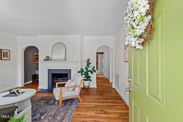 2504 State St, Durham, NC 27704 - living room featuring arched walkways, light wood-style floors, crown molding, and a fireplace with flush hearth