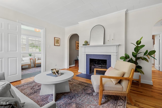 2504 State St, Durham, NC 27704 - living area featuring arched walkways, crown molding, a brick fireplace, and wood finished floors