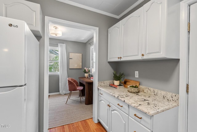 2504 State St, Durham, NC 27704 - kitchen with freestanding refrigerator, white cabinets, light wood finished floors, ornamental molding, and light stone counters