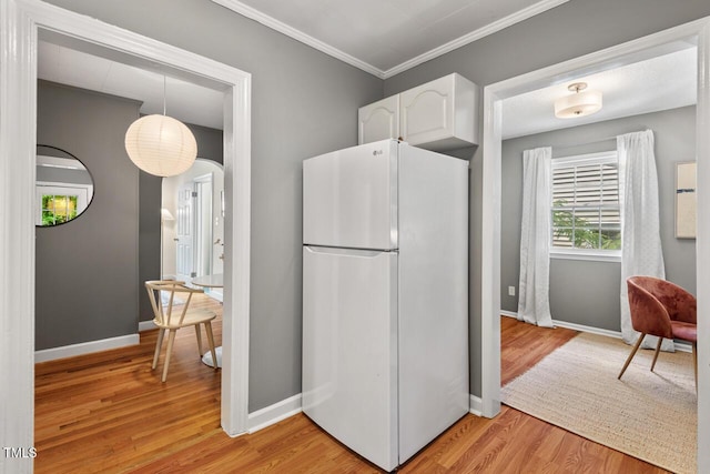 2504 State St, Durham, NC 27704 - kitchen featuring freestanding refrigerator, white cabinets, light wood finished floors, arched walkways, and ornamental molding
