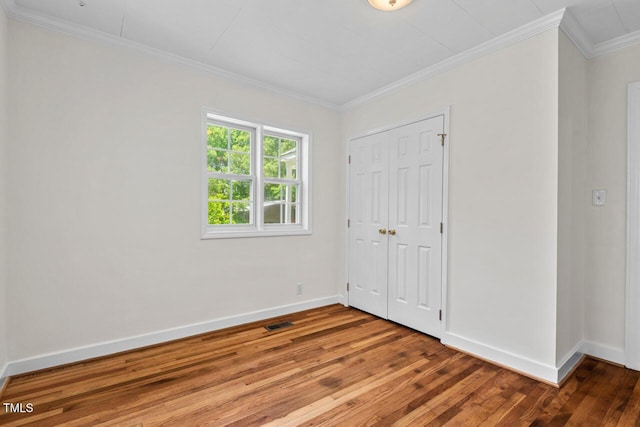 2504 State St, Durham, NC 27704 - unfurnished bedroom with hardwood / wood-style flooring, ornamental molding, and a closet