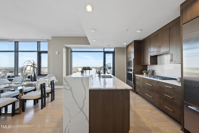 122 N Harrington St Unit 1025, Raleigh, NC 27603 - kitchen with stainless steel appliances, floor to ceiling windows, dark brown cabinetry, modern cabinets, and a center island with sink