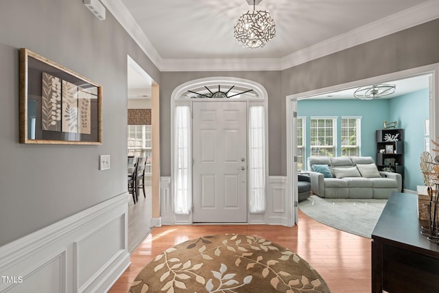 621 Aylestone Dr, Cary, NC 27519 - foyer featuring a chandelier, light wood-type flooring, crown molding, and a wainscoted wall