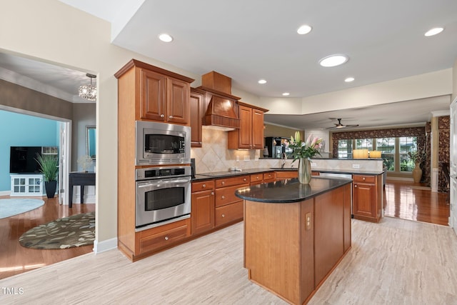 621 Aylestone Dr, Cary, NC 27519 - kitchen with stainless steel appliances, a peninsula, a kitchen island, light wood-style flooring, and brown cabinetry