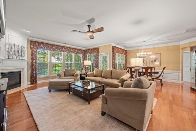 621 Aylestone Dr, Cary, NC 27519 - living area with ceiling fan, crown molding, light wood-style flooring, a chandelier, and a fireplace with flush hearth