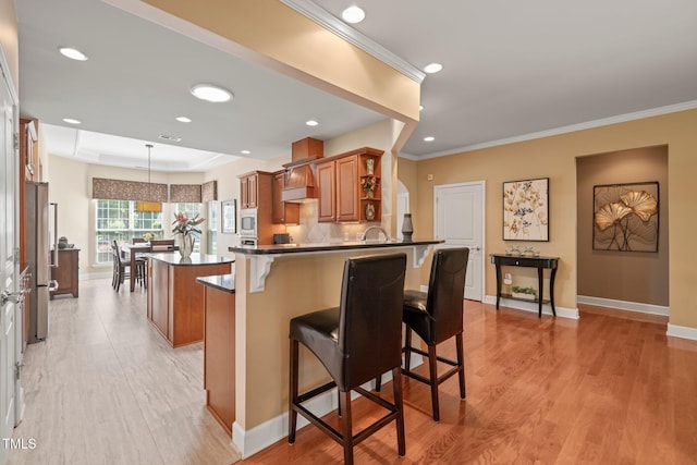 621 Aylestone Dr, Cary, NC 27519 - kitchen featuring brown cabinets, a peninsula, a kitchen island, a breakfast bar, and freestanding refrigerator