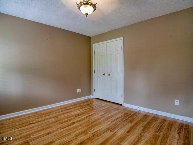 2817 Buckboard Ln, Raleigh, NC 27603 - unfurnished bedroom featuring light wood-style flooring, a closet, and a textured ceiling