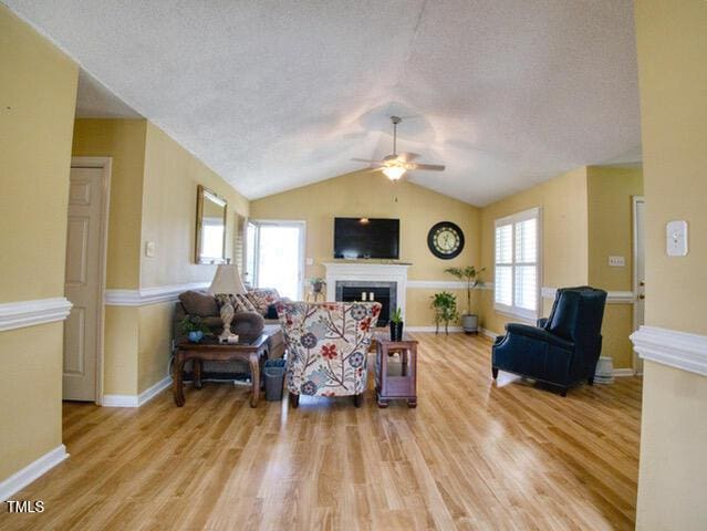 2817 Buckboard Ln, Raleigh, NC 27603 - living room featuring a fireplace, ceiling fan, wood finished floors, a textured ceiling, and lofted ceiling