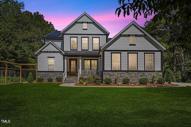 1809 Bowling Rd, Fuquay Varina, NC 27526 - view of front of home featuring stone siding, a front yard, roof mounted solar panels, and covered porch