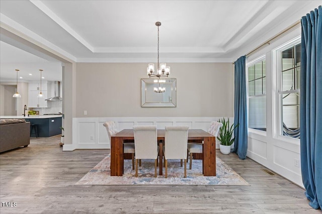 1809 Bowling Rd, Fuquay Varina, NC 27526 - dining area with a raised ceiling, a chandelier, light wood finished floors, a decorative wall, and wainscoting