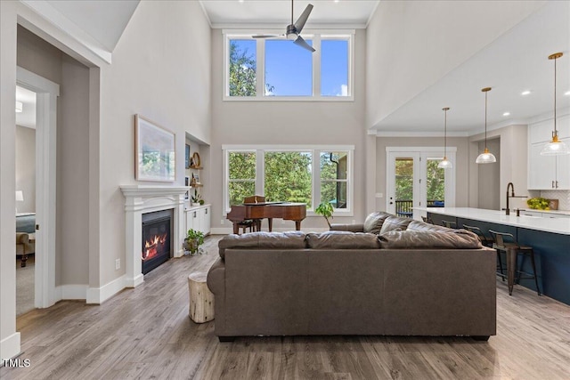 1809 Bowling Rd, Fuquay Varina, NC 27526 - living area featuring a high ceiling, a ceiling fan, light wood finished floors, a glass covered fireplace, and french doors