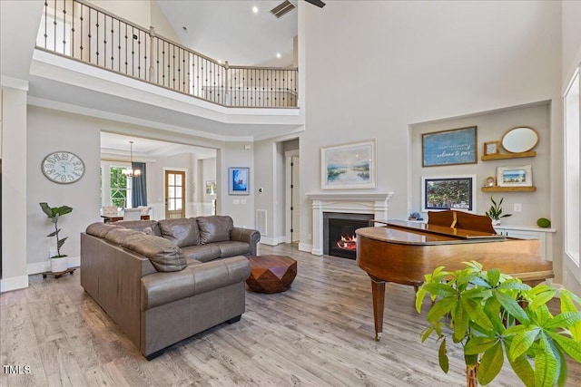 1809 Bowling Rd, Fuquay Varina, NC 27526 - living area featuring a towering ceiling, wood finished floors, a lit fireplace, and a chandelier