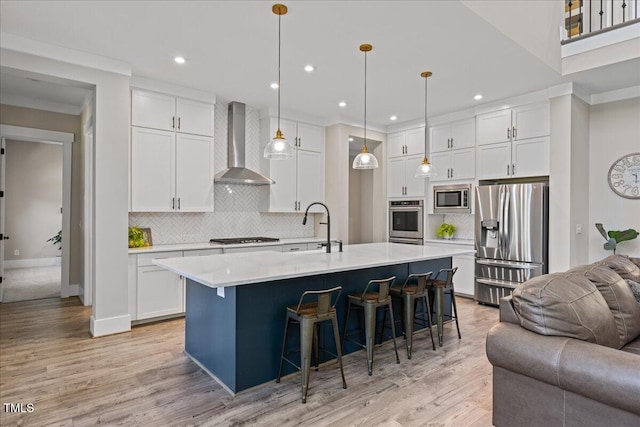1809 Bowling Rd, Fuquay Varina, NC 27526 - kitchen featuring stainless steel appliances, wall chimney exhaust hood, open floor plan, white cabinetry, and a breakfast bar