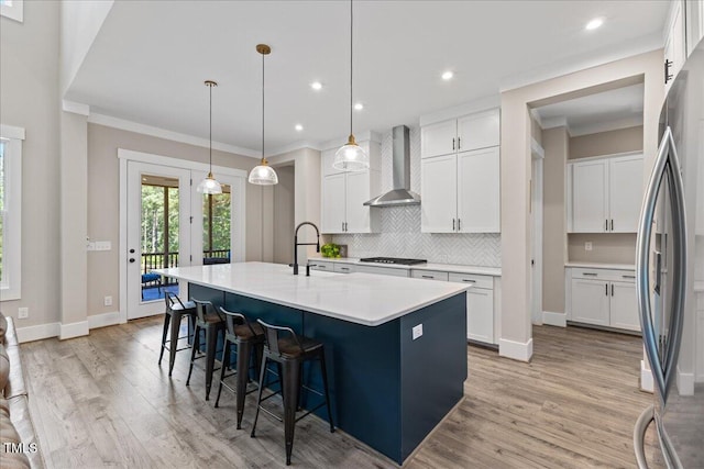 1809 Bowling Rd, Fuquay Varina, NC 27526 - kitchen featuring wall chimney range hood, tasteful backsplash, freestanding refrigerator, light wood-type flooring, and white cabinetry