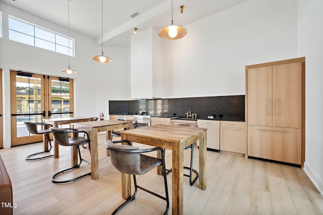 1508 Wader Cir, Knightdale, NC 27545 - kitchen featuring a towering ceiling, stainless steel dishwasher, light wood finished floors, light brown cabinets, and tasteful backsplash