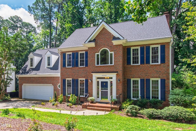 4309 Omni Pl, Raleigh, NC 27613 - colonial inspired home featuring an attached garage, brick siding, concrete driveway, and roof with shingles