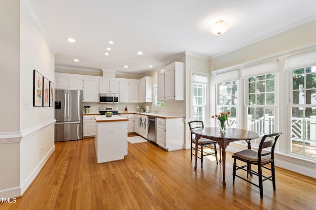 4309 Omni Pl, Raleigh, NC 27613 - kitchen with stainless steel appliances, crown molding, a kitchen island, light countertops, and white cabinets