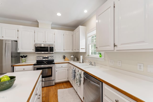 4309 Omni Pl, Raleigh, NC 27613 - kitchen with stainless steel appliances, ornamental molding, white cabinets, light countertops, and light wood finished floors