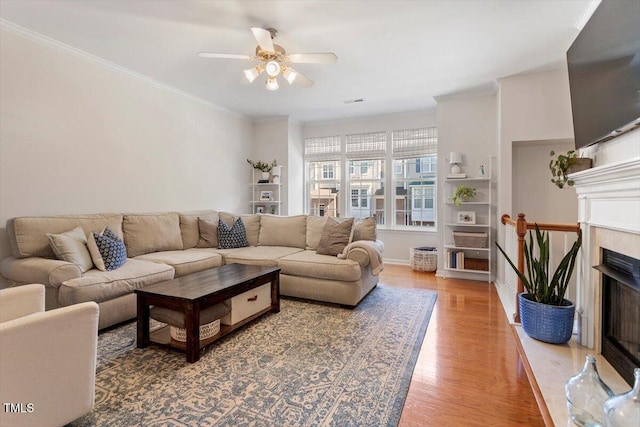 4533 Pale Moss Dr, Raleigh, NC 27606 - living room featuring light wood-style flooring, ceiling fan, a fireplace, and crown molding